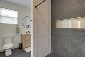 Ein Badezimmer mit Toilette, Waschbecken, Spiegel und Duschbereich.