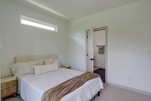 Ein Schlafzimmer mit Bett, Nachttischen, einer Tür und einem Fenster.