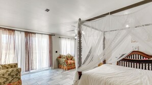 Un dormitori amb un llit amb cortines, un sofà i una cadira.