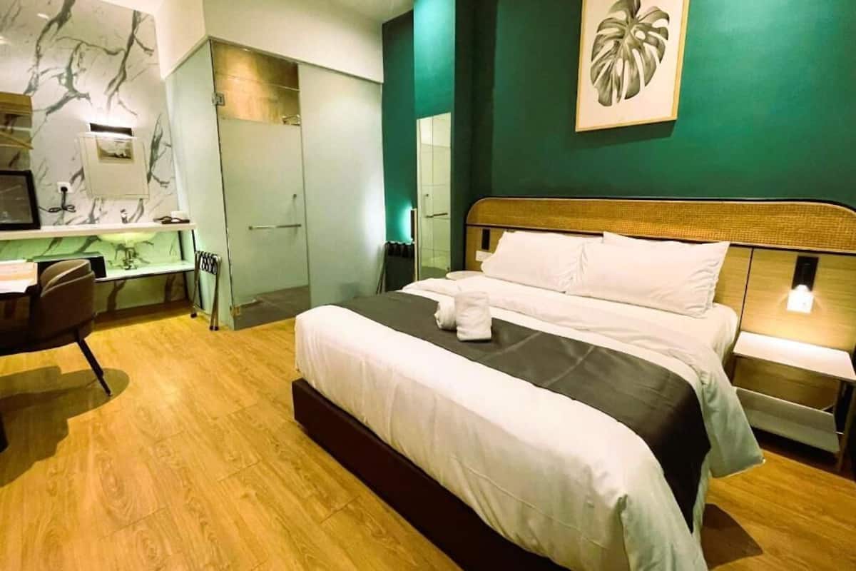 Ein Hotelzimmer mit Bett, Nachttisch, Schreibtisch, Stuhl und einem großen Spiegel.