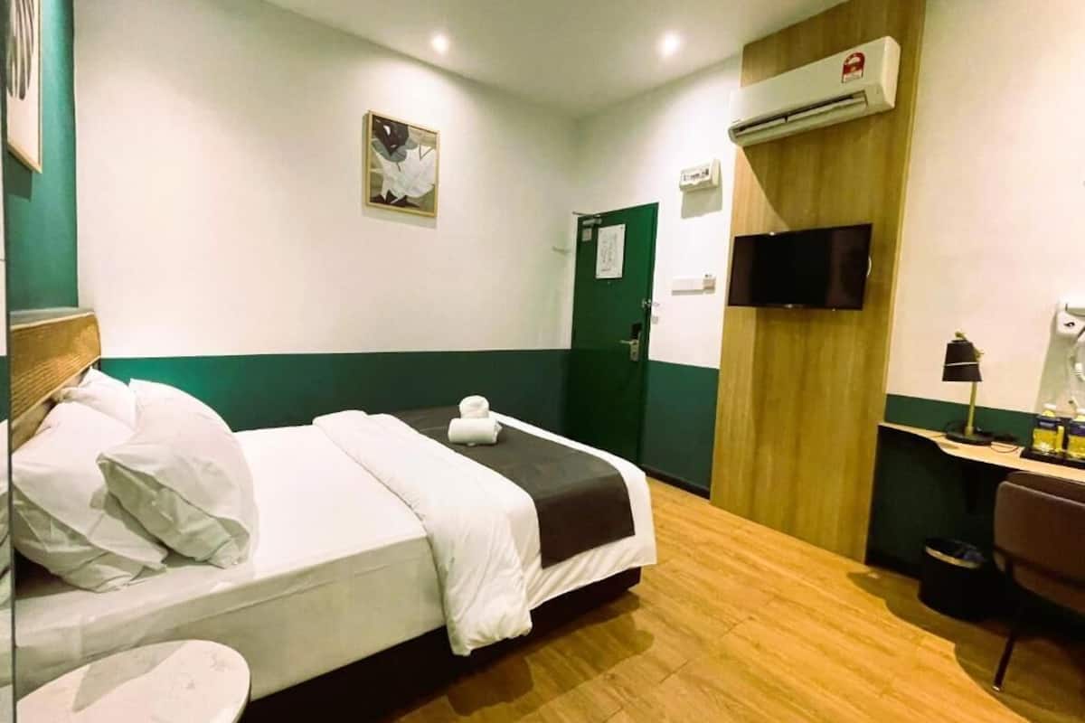 Ein Hotelzimmer mit Bett, Schreibtisch, Stuhl, Klimaanlage und Fernseher.