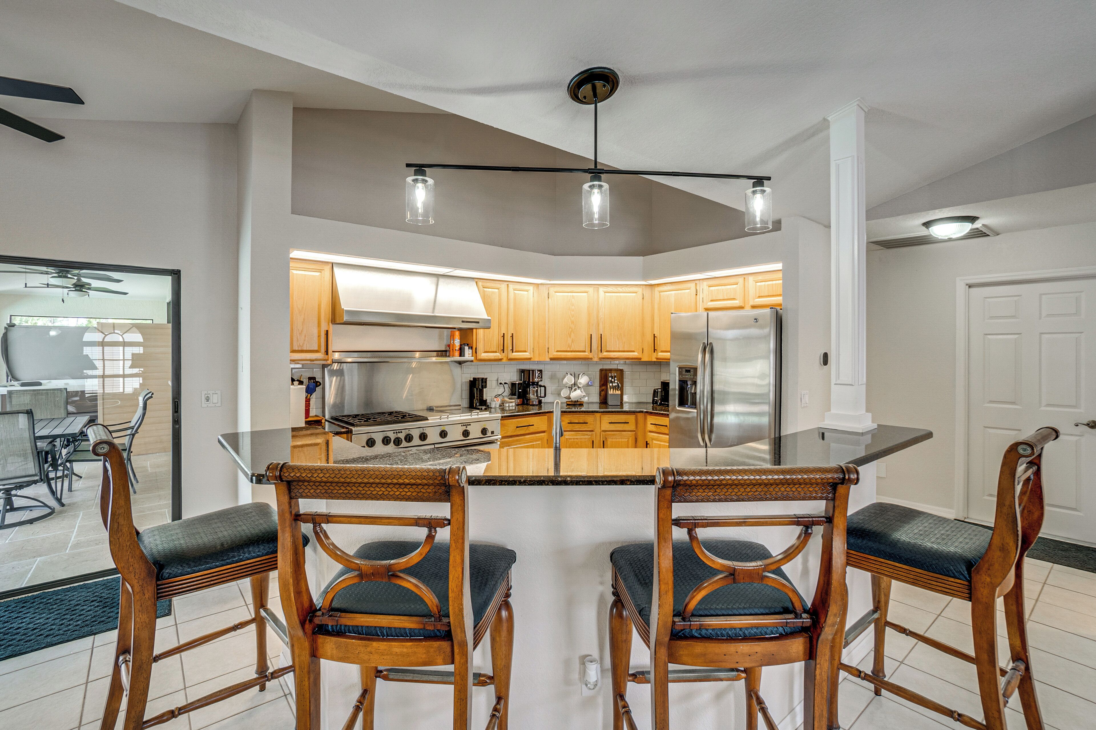 A modern kitchen with wooden cabinets, a central island, and a dining area with wooden chairs.