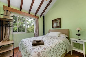 A bedroom with a bed, a bedside table, a window, and a wardrobe.