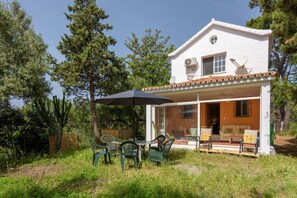 A two-story house with a patio area featuring outdoor furniture and a large umbrella.
