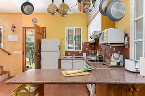 A kitchen with granite countertops, a refrigerator, a microwave, and a window with a view of greenery.
