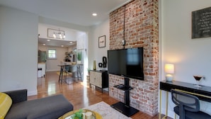 A modern living room with a flat-screen TV, a dining area, and a kitchen in the background. - Extended East Knoxville Stay, 2 Mi to Dtwn! (Knoxville)