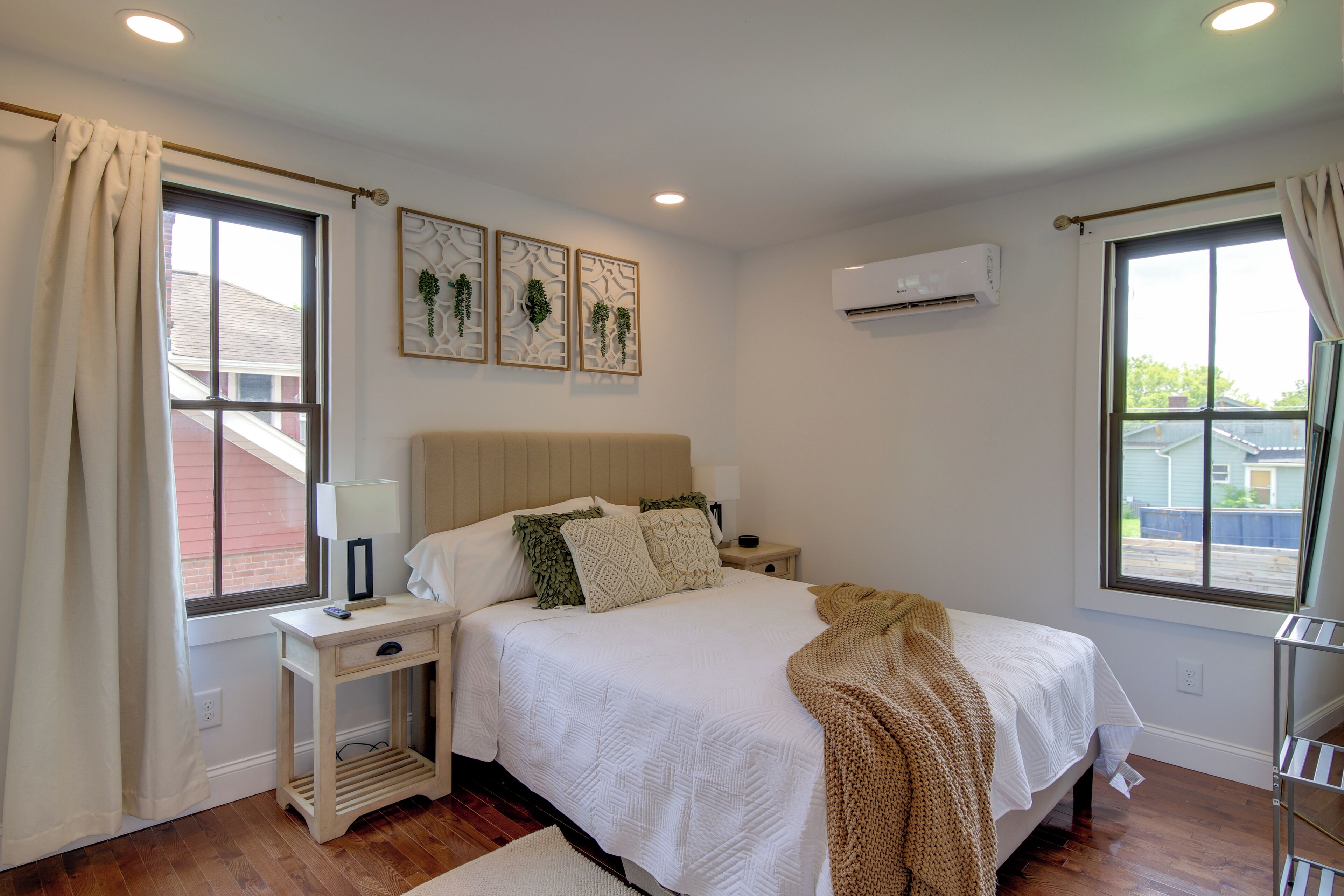 A bedroom with a bed, bedside tables, a window, and an air conditioning unit.