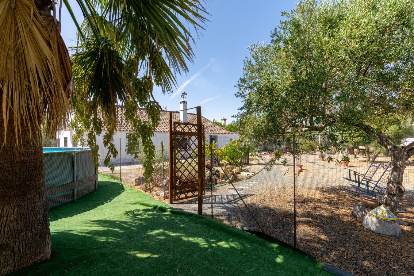 Un espace extérieur clos, doté d’une piscine, d’une pergola et d’un bâtiment dont le toit est recouvert de tuiles.