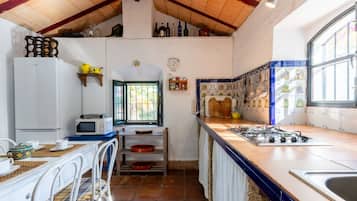 Cocina compacta con microondas, estufa y ventana con vistas.