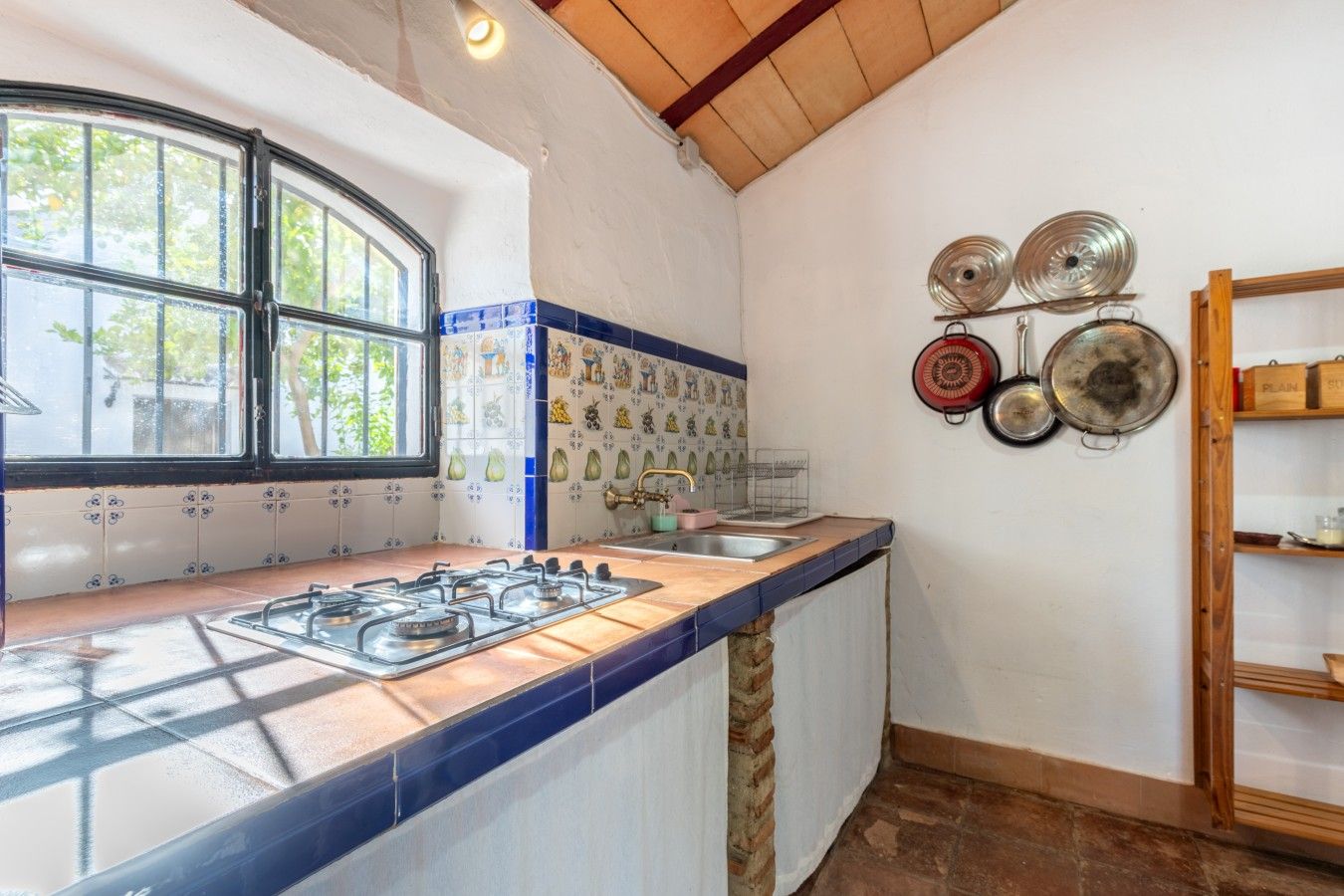 A kitchen with a gas stove, a window, and a wall-mounted pot rack.