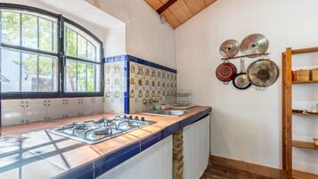 A kitchen with a gas stove, a window, and a wall-mounted pot rack.