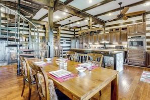 A spacious kitchen with wooden beams, a dining area with a large wooden table and chairs, and a spiral staircase. - Shenandoah NP Escape w/ Deck: Hike, Soak + Fish (Stanley)