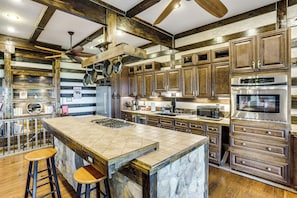 A kitchen with a large island, wooden cabinets, a microwave, and a stainless steel oven. - Shenandoah NP Escape w/ Deck: Hike, Soak + Fish (Stanley)
