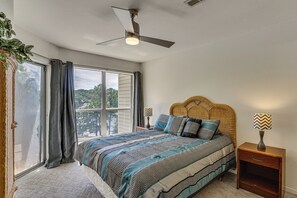 A bedroom with a bed, a ceiling fan, a window with curtains, and a nightstand with a lamp. - Unwind Poolside, Walk to Beach! Ozarks Getaway (Osage Beach)