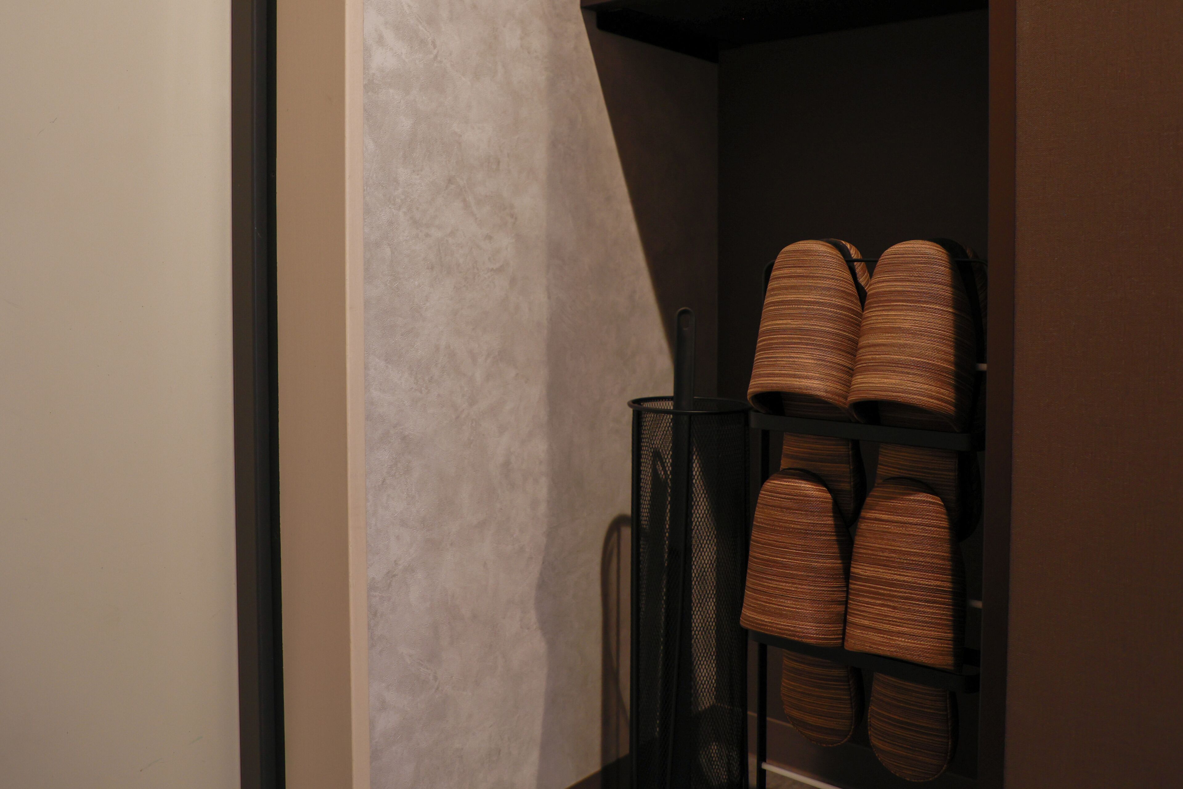Un couloir avec un meuble à chaussures et un mur à motifs.