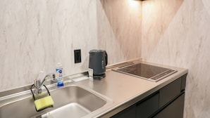 A modern kitchen with a stainless steel sink, a kettle, and a built-in induction cooktop. - INNEST HAKATA (Fukuoka City)