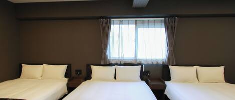 A hotel room with two beds, a window with curtains, and a bedspread with a floral pattern.