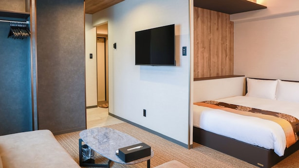 A modern hotel room with a bed, a flat-screen TV, a small table, and a seating area. - INNEST HAKATA (Fukuoka City)