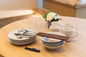 A neatly set dining table with plates, cutlery, and cups, accompanied by a small vase with a white flower. - INNEST HAKATA (Fukuoka City)