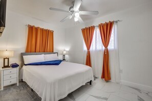 A bedroom with a bed, nightstands, a ceiling fan, and orange curtains. - Close to Hard Rock Stadium! Group Getaway w/ Yard (Miami Gardens)
