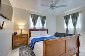 Un dormitorio con cama de madera, una mesita de noche, una lámpara y un ventilador de techo.