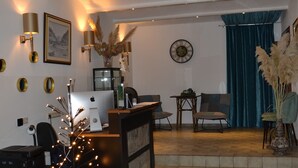 A reception area with a desk, chairs, a clock, and a staircase leading to a seating area. - Hotel Balduin (Balduinstein)