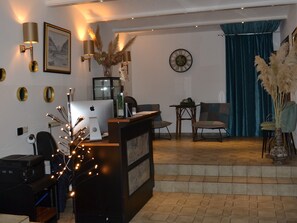Zona de recepció amb taulell, cadires, rellotge i escala que condueix a una zona de seients.