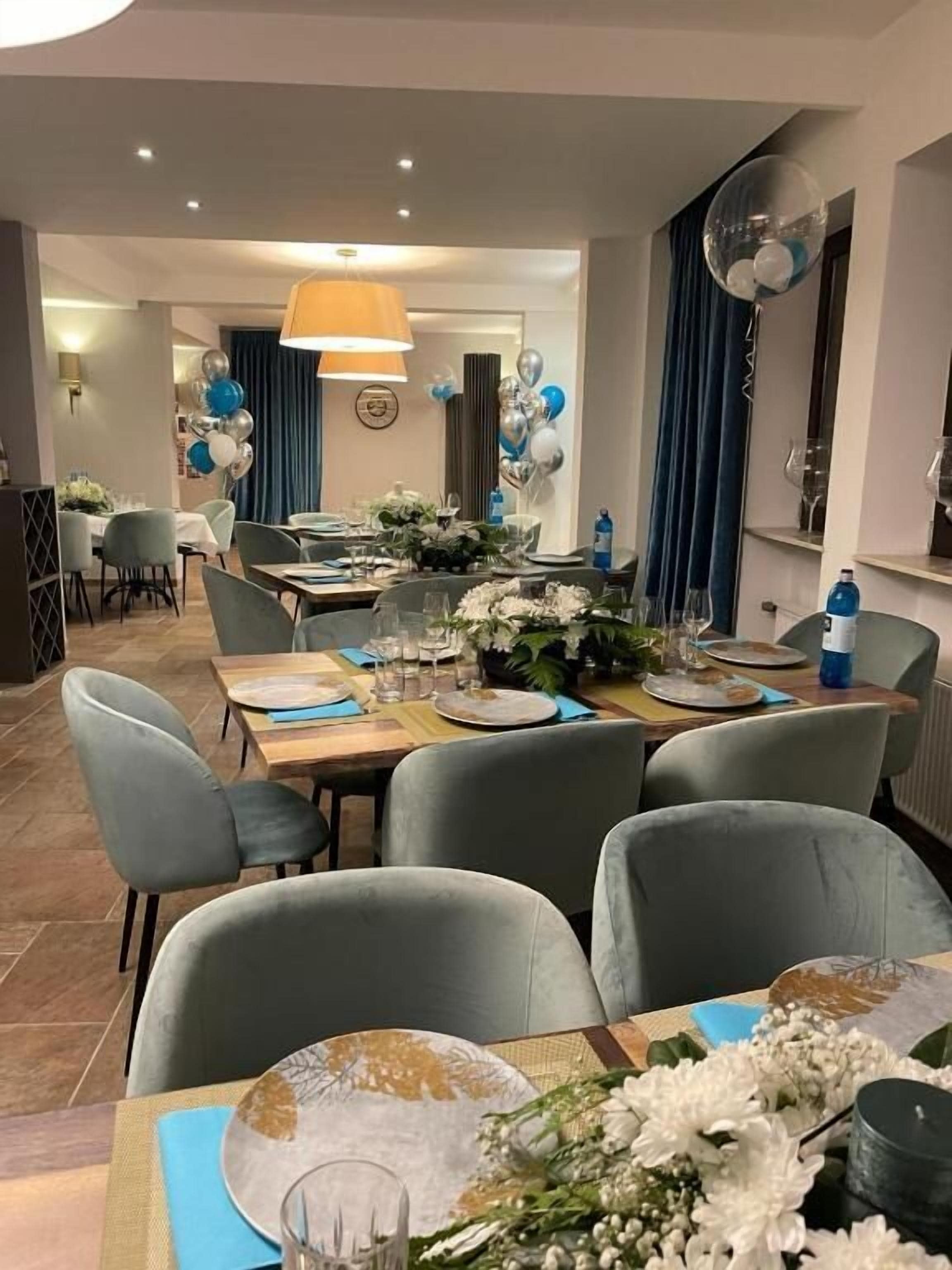 Comedor con mesas dispuestas para cuatro, sillas y una lámpara decorativa grande.