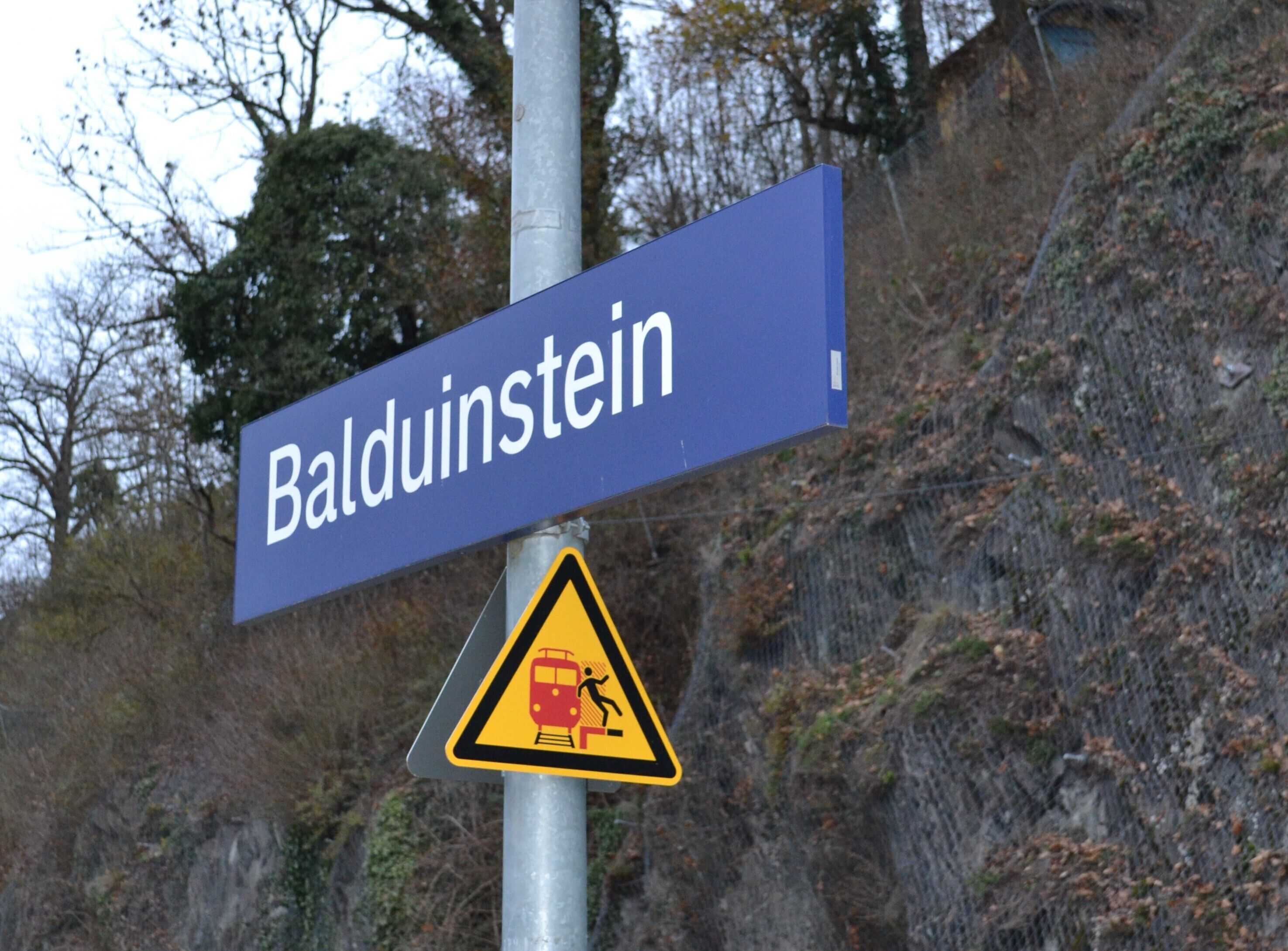 Ein Straßenschild für 'Baldunstein' und ein Warnschild für eine Bahnübergang.