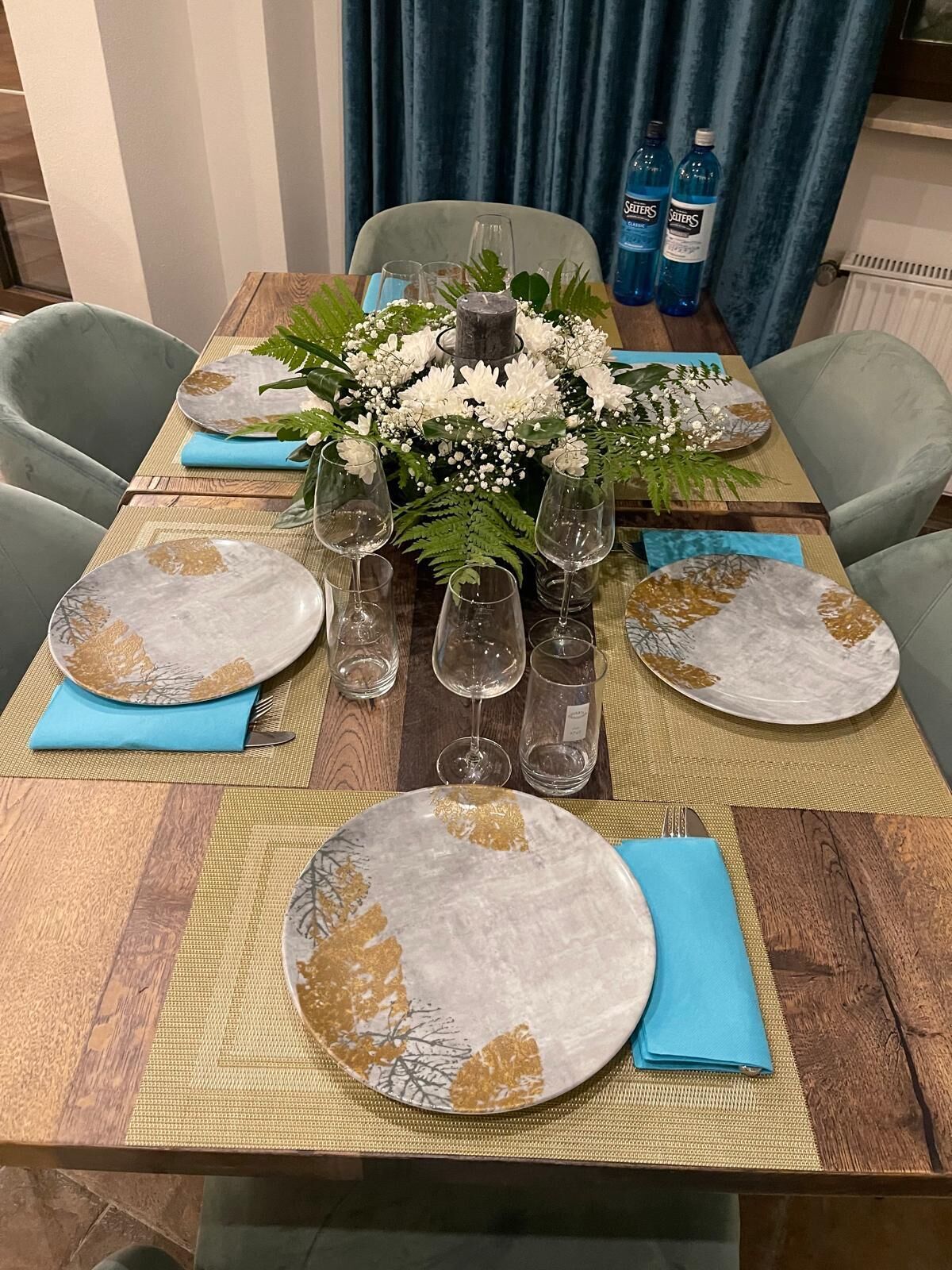 A dining table set with plates, glasses, and a centerpiece.