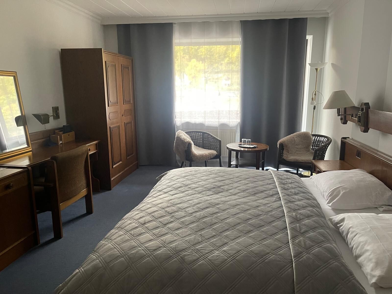 Ein Hotelzimmer mit einem Bett, zwei Stühlen, einem Schreibtisch und einem Kleiderschrank.
