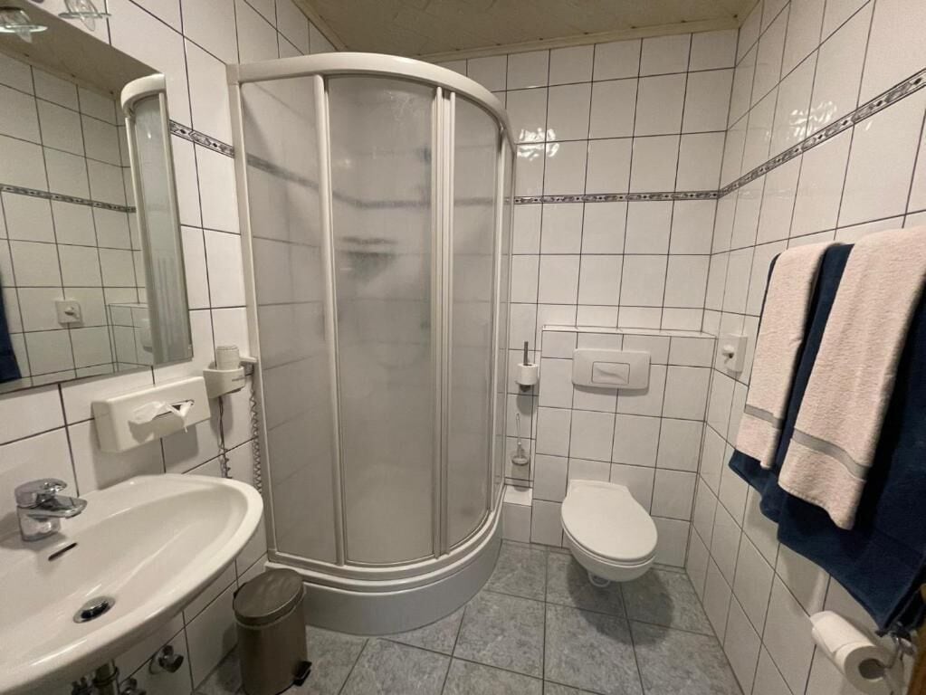 A bathroom with a shower, toilet, sink, and towel rack.
