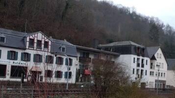 Un edificio con un restaurante llamado 'Baldwin' en la planta baja, rodeado de árboles y colinas.