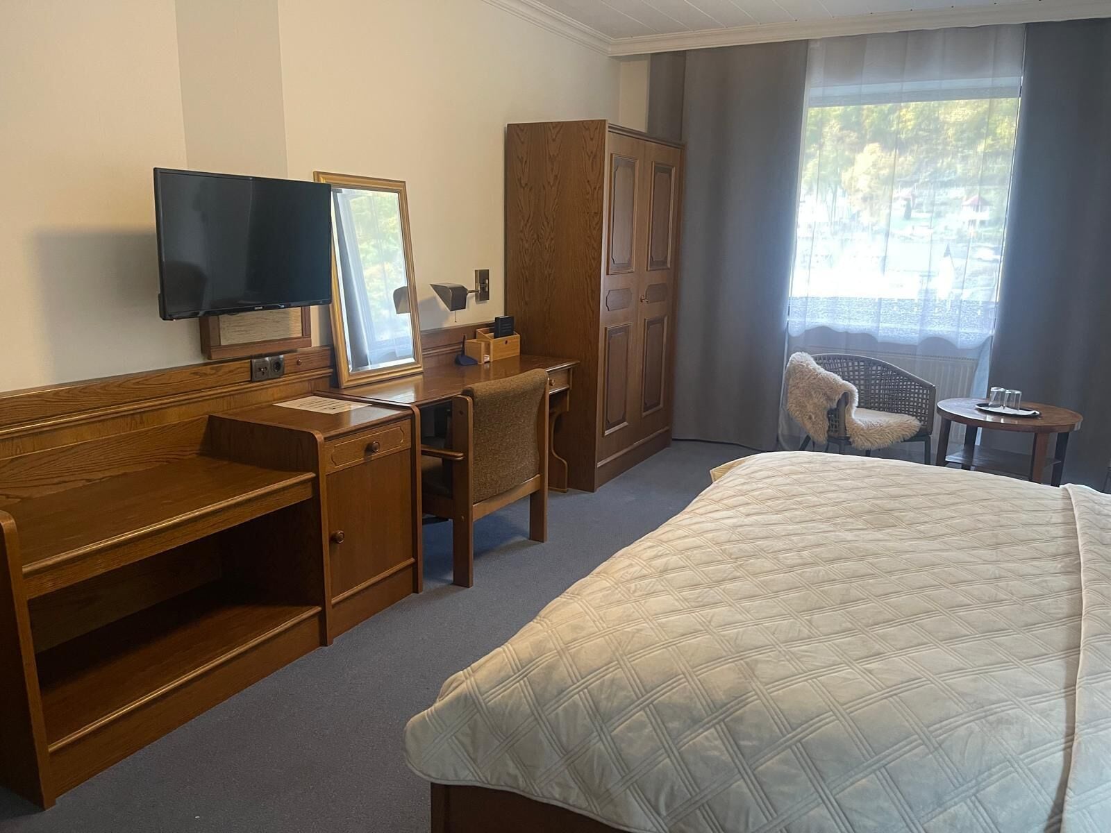Een hotelkamer met een bed, een bureau met televisie, een kledingkast, een stoel en een kleine tafel.