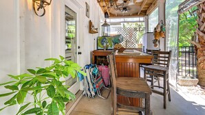 A covered outdoor dining area with wooden furniture, a table, chairs, and a hanging light fixture. - Walk to the Water! Murrells Inlet Getaway (Murrells Inlet)
