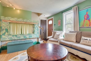 A cozy living room with a stone fireplace, a round wooden coffee table, a sofa, and a window with curtains. - Family Mashpee Eco-Retreat - Naturally Cape Cod! (Mashpee)