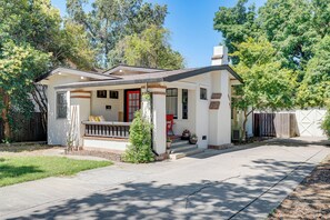 Ein eingeschossiges Haus mit einer Veranda, einer rotem Tür und einer Garage.