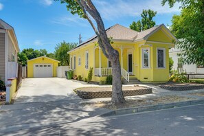 Ein gelbes Einfamilienhaus mit Garage, einer Veranda und einem Baum im Vorgarten.
