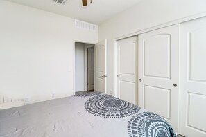 Ein Schlafzimmer mit einem Bett, einer Tür und einem Gang zu einem anderen Raum.