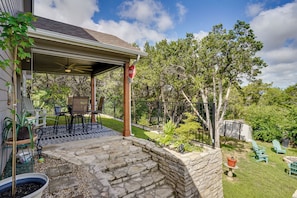 A covered patio area with a ceiling fan, outdoor furniture, and a stone wall. - Walk to Lake Granbury: Home w/ Fire Pit! (Granbury)