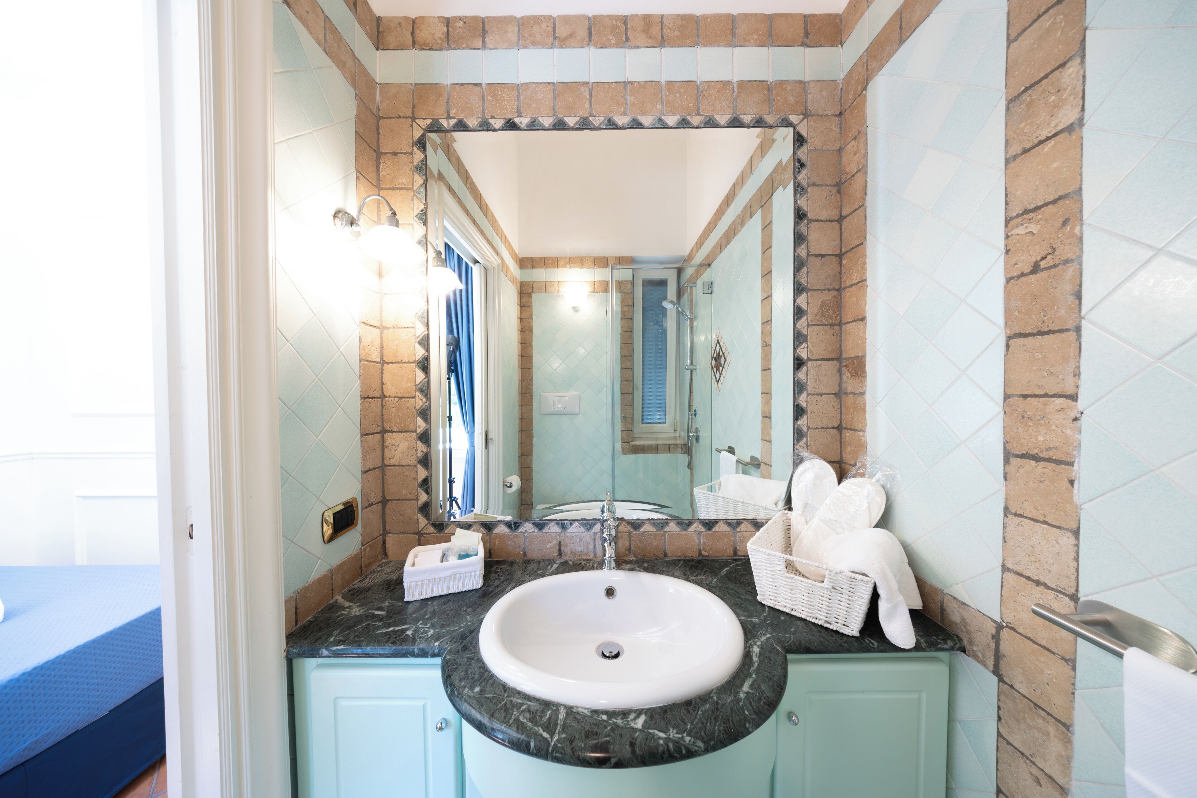 A bathroom with a sink, mirror, and tiled walls.