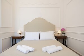 A neatly made bed with two pillows, two bedside tables with lamps, and a potted plant on one table. - Villa Preziosa - Panoramic Sea View (Capri)