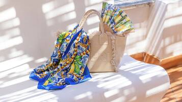 A beige handbag with a floral pattern and a matching umbrella on a white bench.