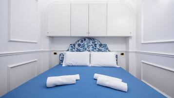 Une chambre avec un lit, des murs blancs et une tête de lit bleue.