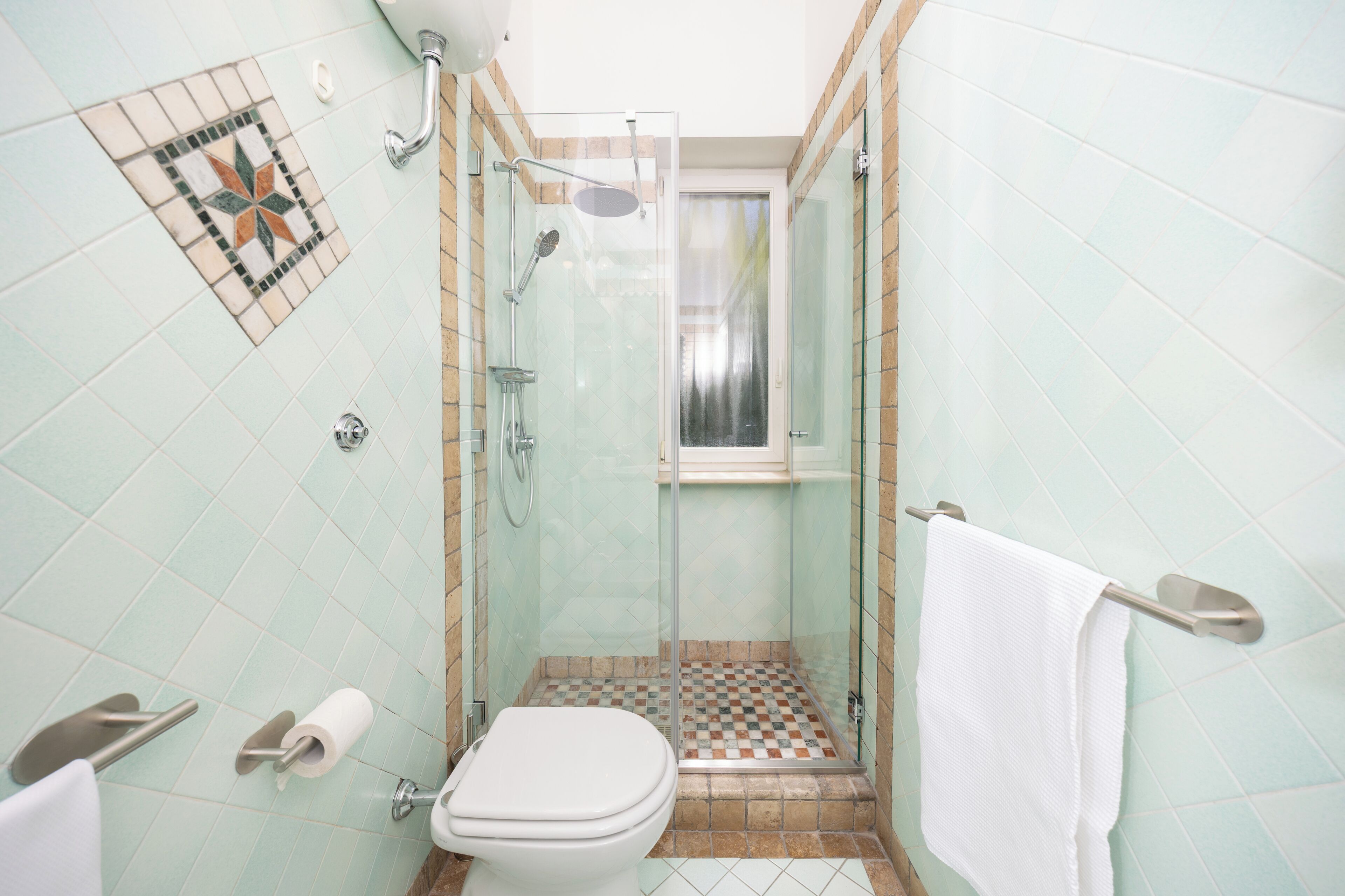 Un baño con inodoro, ducha y puerta de cristal.