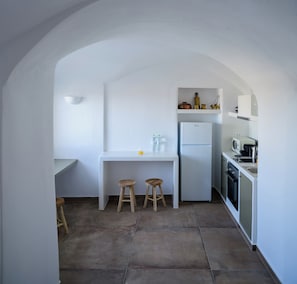 A kitchen with a white countertop, two stools, a refrigerator, and a microwave. - A Cycladic home with a private pool and sea view, away from the crowds! (Exo Gonia)