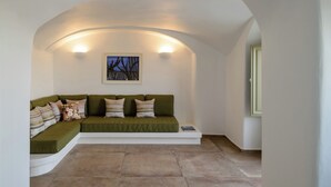 A cozy room with a green sofa, a framed picture, and a tiled floor. - A Cycladic home with a private pool and sea view, away from the crowds! (Exo Gonia)