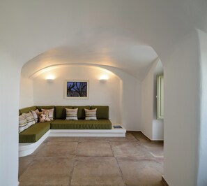 A cozy room with a green sofa, a framed picture, and a tiled floor. - A Cycladic home with a private pool and sea view, away from the crowds! (Exo Gonia)