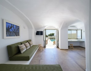 Ein modernes Interieur mit einem grünen Sofa, einem Gemälde und Blick auf einen Außenpool.