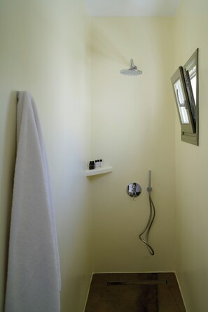A small bathroom with a shower, a towel rack, and a shelf with toiletries. - Little Garden Suite, Kaminia Holiday Homes (Exo Gonia)